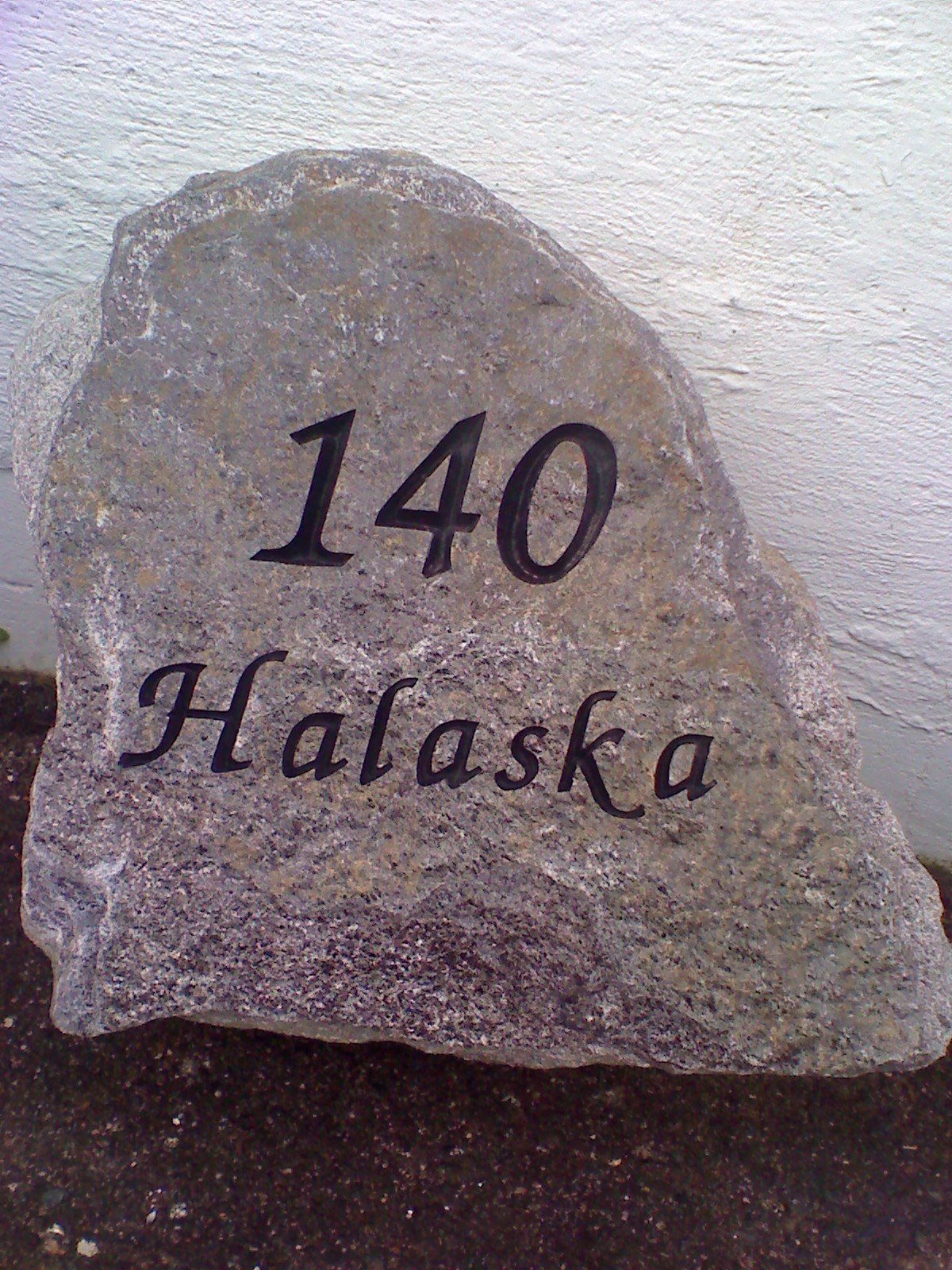 A natural granite boulder cut with the house number 140 and the name Halaska
