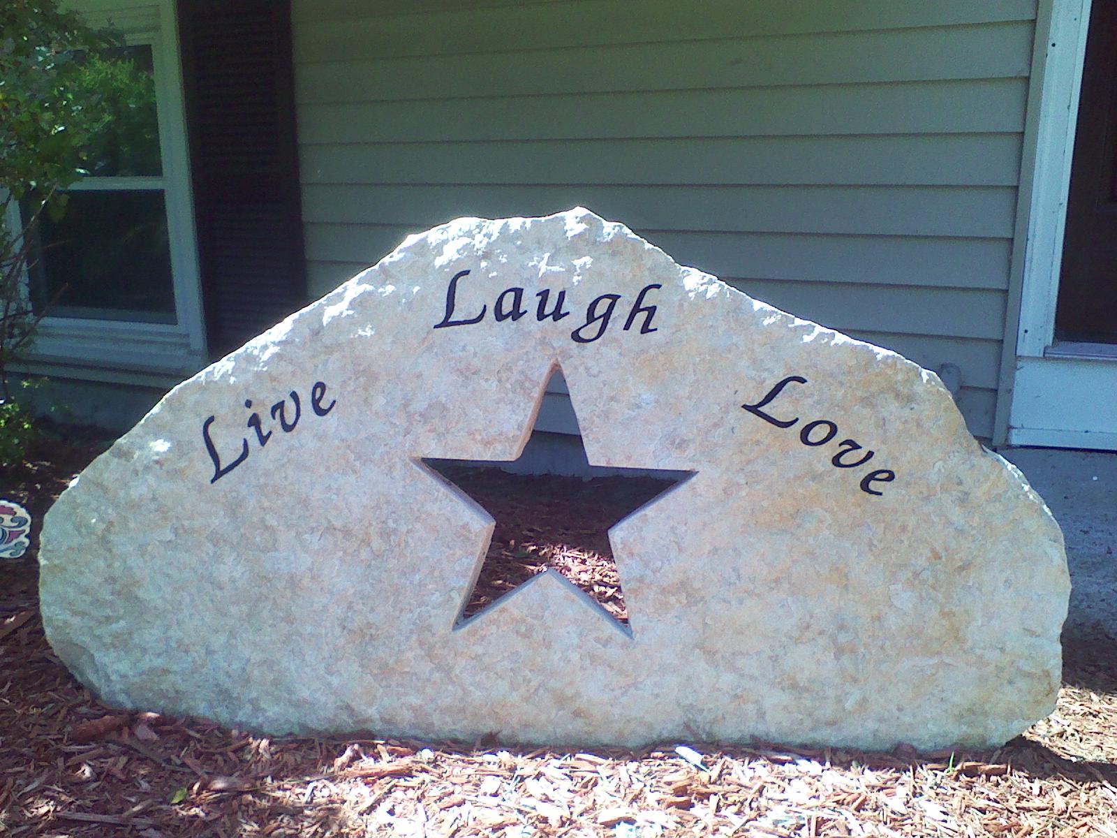 A pale fieldstone lettered Live, Laugh and Love in script, with a star cut clean through the stone
